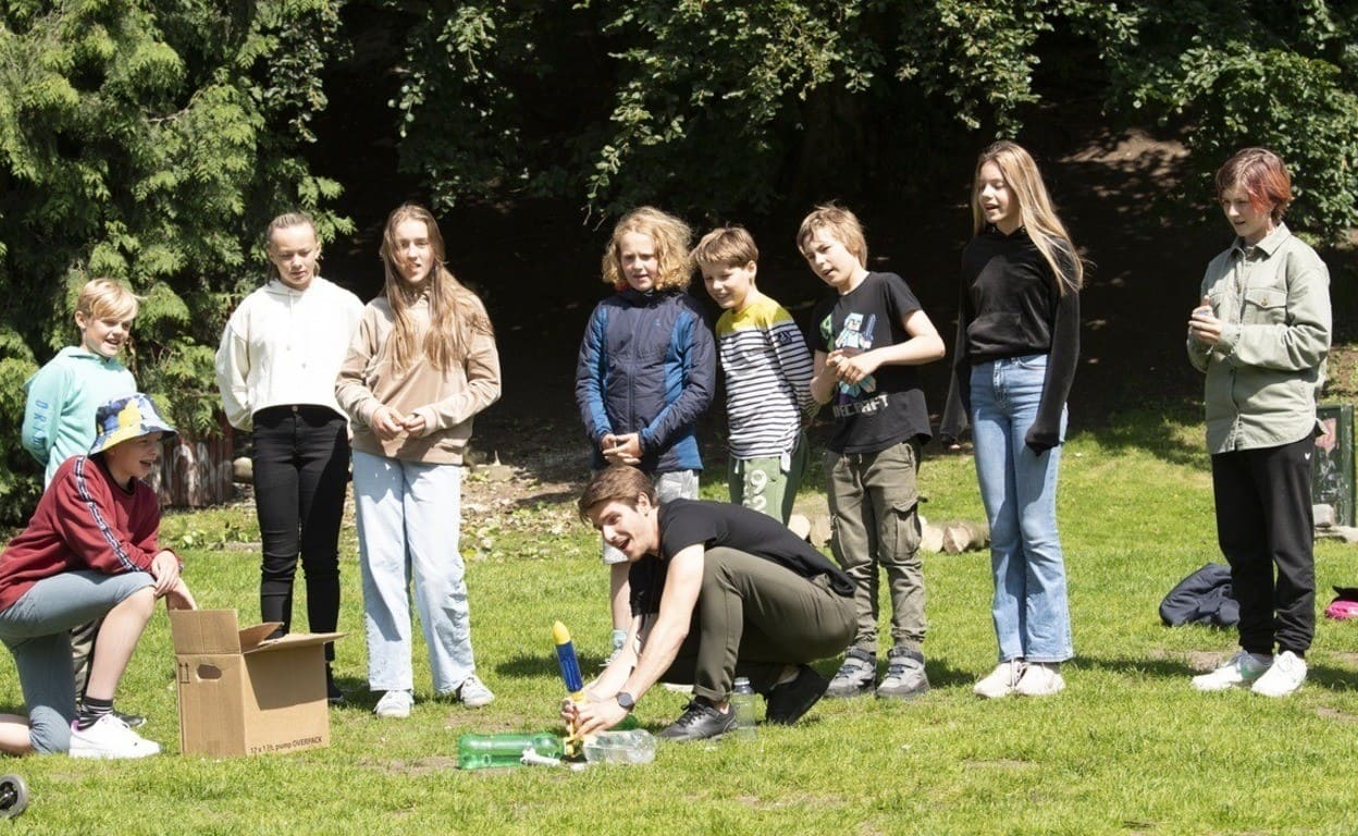 class in a park making a rocket fly with bottles